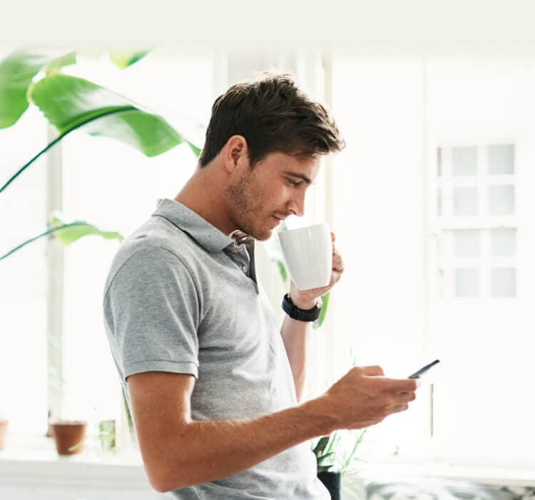 Mand drikker kaffe med en mobiltelefon i hånden