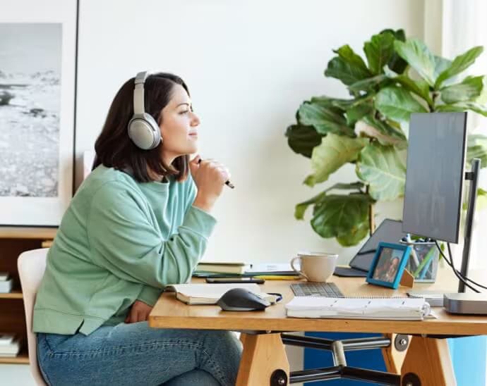 Kvinde med hovedtelefoner, der holder en pen og kigger på en pc-skærm