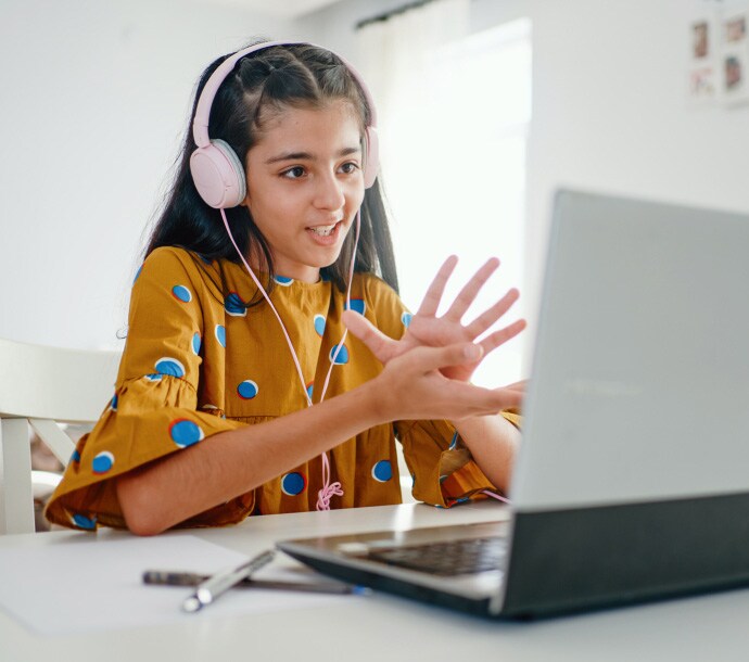 pige sidder ved et skrivebord med en bærbar computer og starter Norton Family.