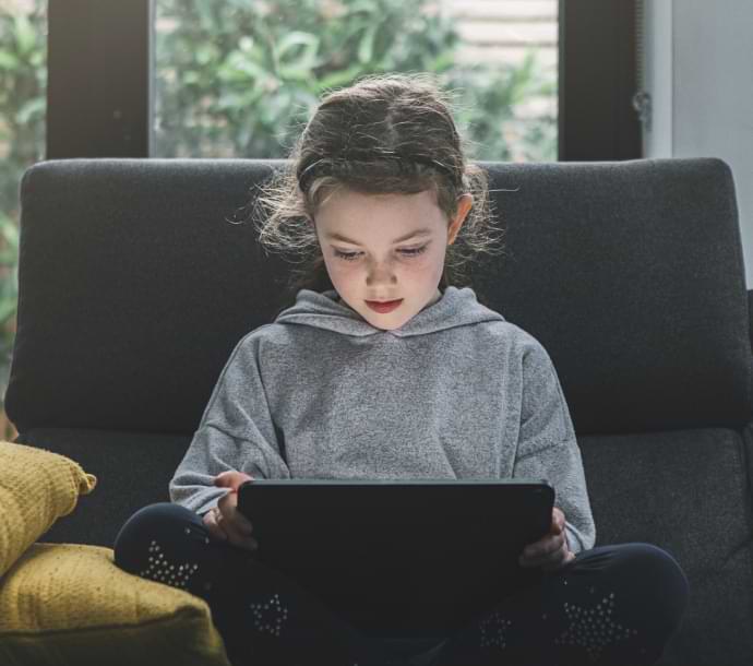 pige sidder på en sofa med en bærbar computer og starter Norton Family.