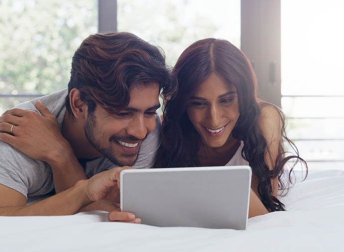 Mand og kvinde griner, mens de ser på en tablet