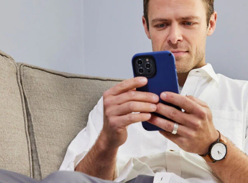 Mand på en sofa kigger på en telefon