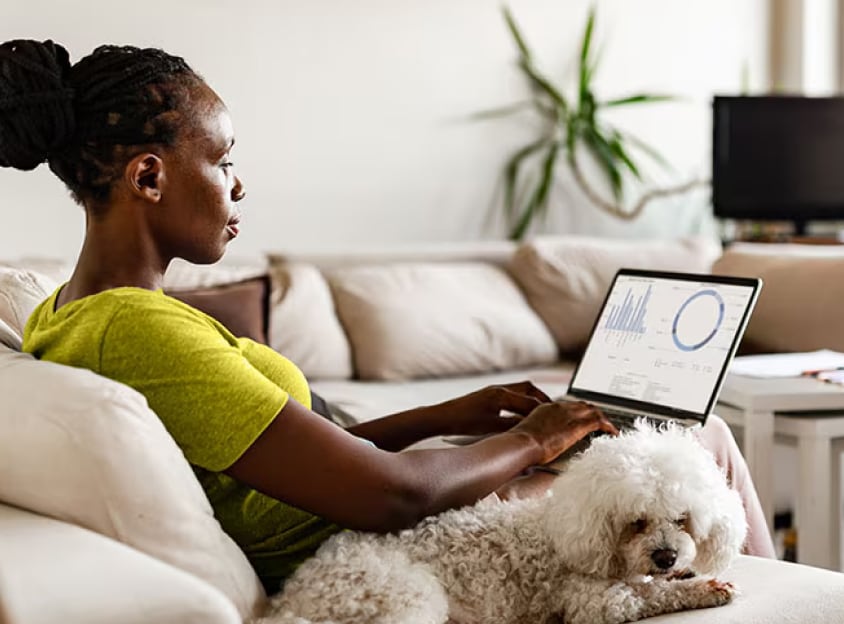 Siddende kvinde med hund arbejder på bærbar computer